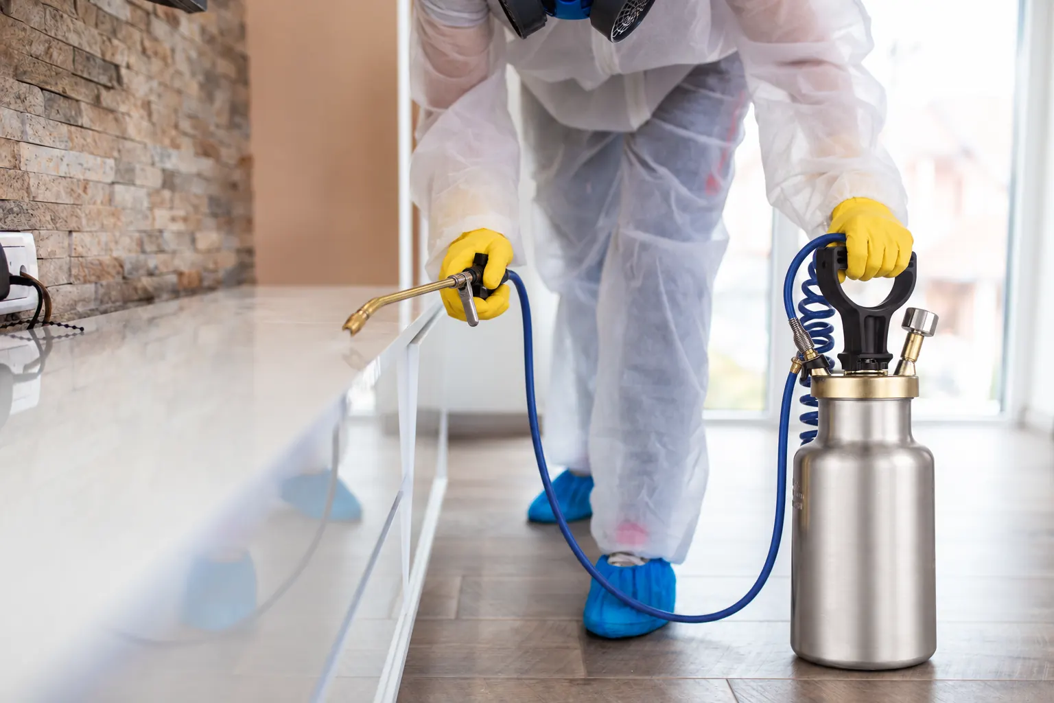 Pest-management professional using a metal compression sprayer during an indoor treatment