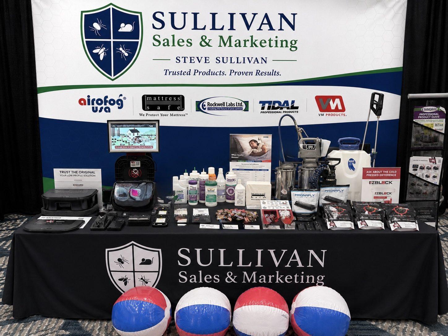 Represented products laid out on the Sullivan Sales and Marketing display table: baits, dusts, sprayers, a fogger, bait stations, and fly-control hardware